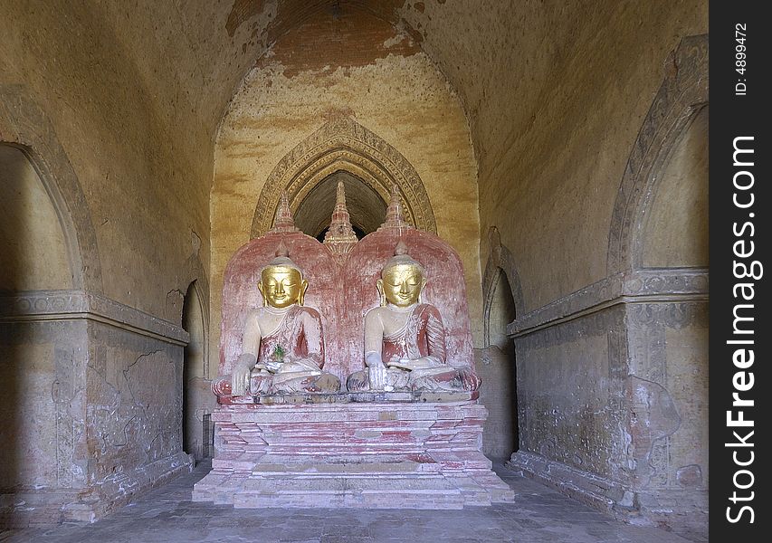 Myanmar Bagan; statue in dhammayangyi Temple; indoor archiecture and light pink background for this two seated buddha. Myanmar Bagan; statue in dhammayangyi Temple; indoor archiecture and light pink background for this two seated buddha