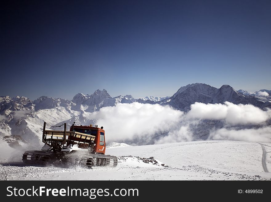 Snowcat on a slope and mountains behind. Snowcat on a slope and mountains behind