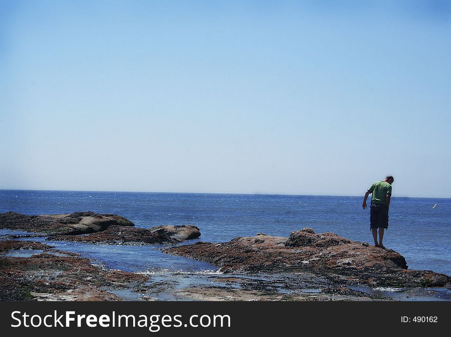 Man stands out on rocks during low tide. Space for copy. Man stands out on rocks during low tide. Space for copy.