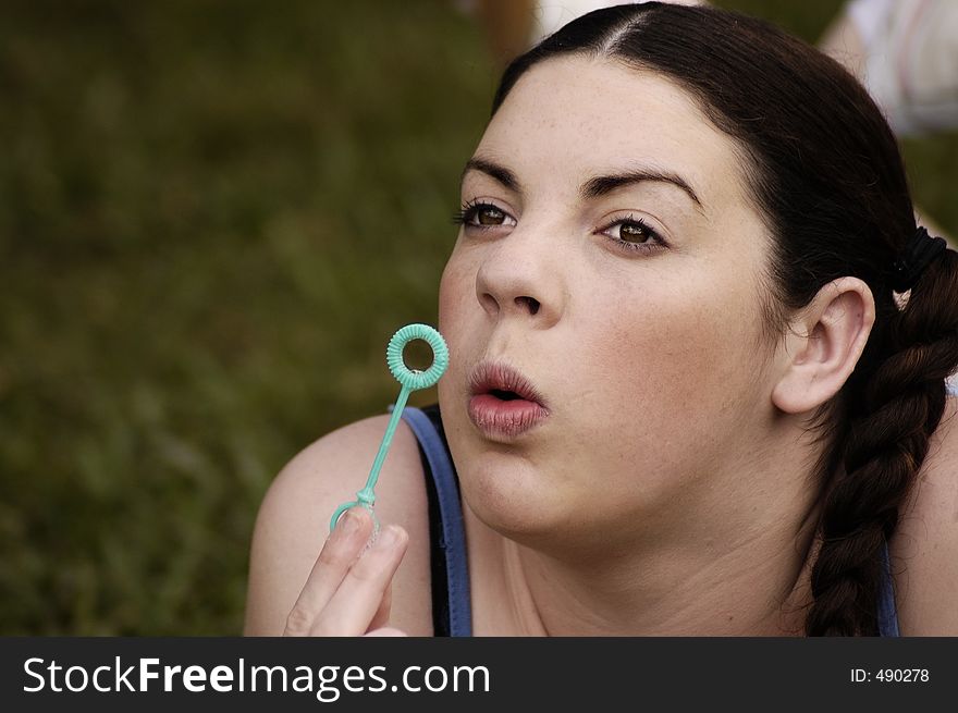 A young female adult blows bubbles while daydreaming. A young female adult blows bubbles while daydreaming.