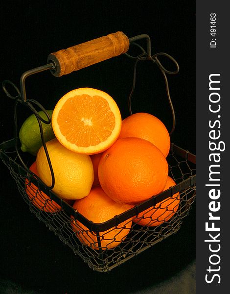 Citrus fruit in a wire basket over black. Citrus fruit in a wire basket over black