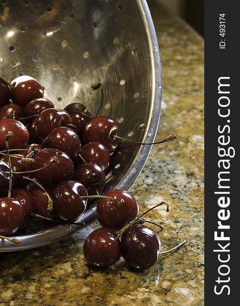 Freshly picked and washed cherries fall from the colander, ready to be eaten. Freshly picked and washed cherries fall from the colander, ready to be eaten.