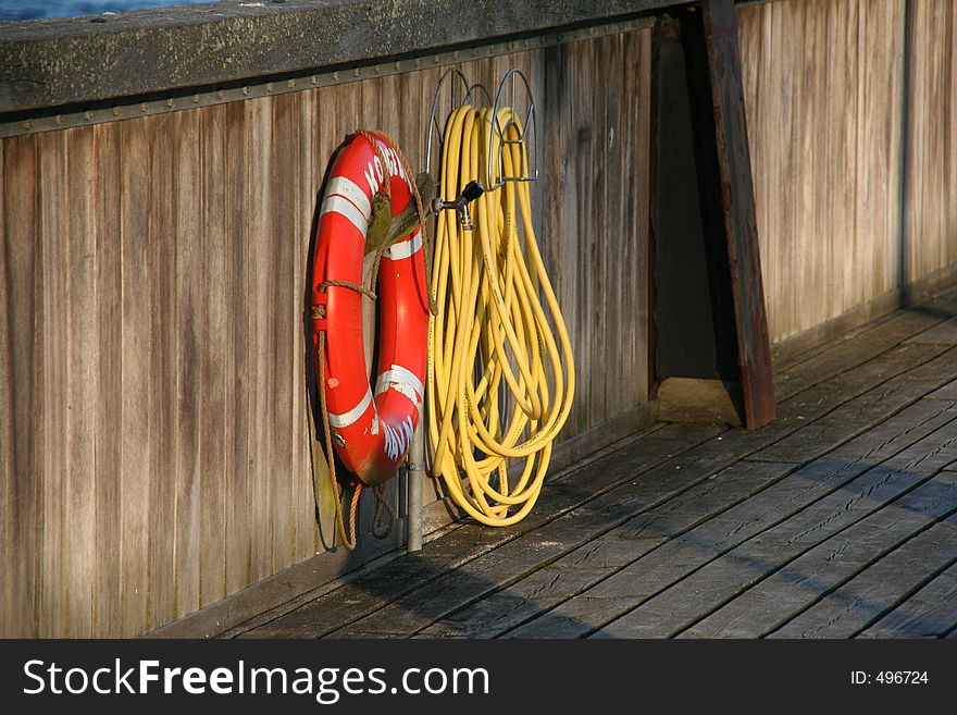 Lifebelt and hose at a small harbour in the eventing sun. Lifebelt and hose at a small harbour in the eventing sun