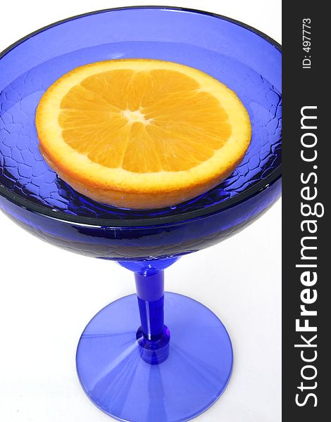 Half an orange floats in a blue glass. Half an orange floats in a blue glass