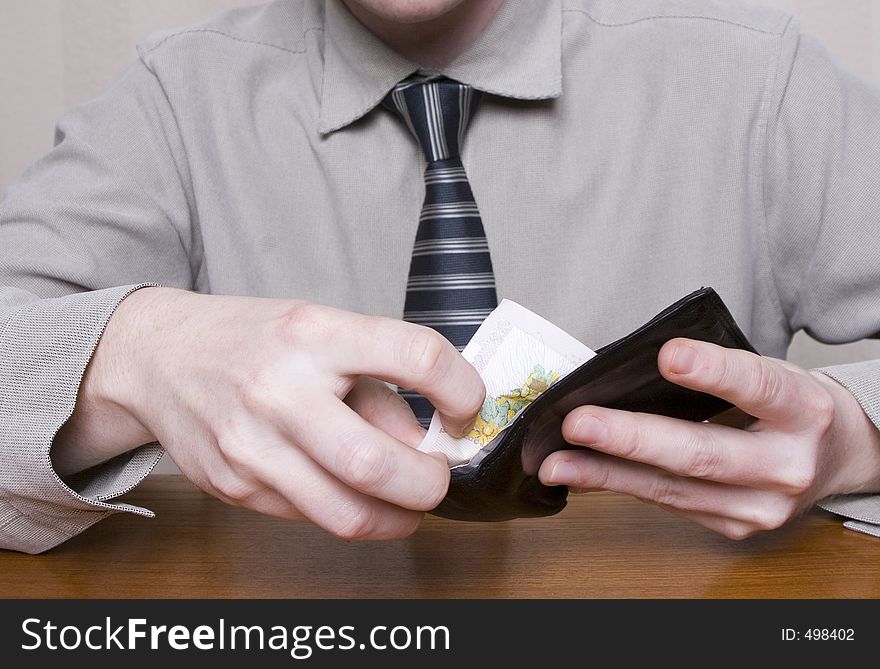 Man, getting notes out of his wallet, paying for an item. Man, getting notes out of his wallet, paying for an item