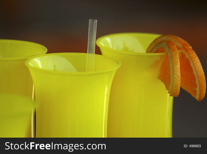 Bright yellow cocktail glasses with orange slice garnish. Bright yellow cocktail glasses with orange slice garnish