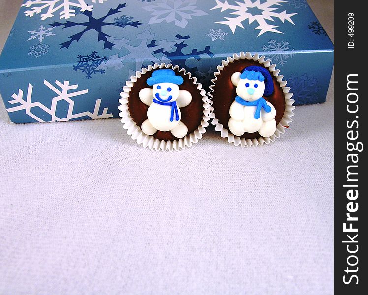 Snowman on chocolate against a box of chocolates, with snowflakes. Snowman on chocolate against a box of chocolates, with snowflakes.