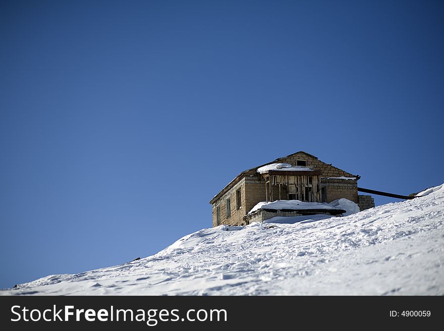 Abandoned house in high mountains, blue sky, winter