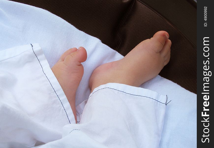 Small legs sleeping baby on white bedsheet