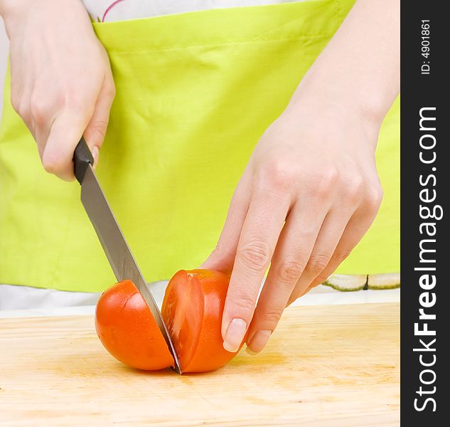 Woman cooking,cutting tomato on a wooden board