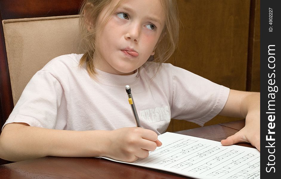 Portrait of thoughtful young girl sat at table writing homework. Portrait of thoughtful young girl sat at table writing homework.