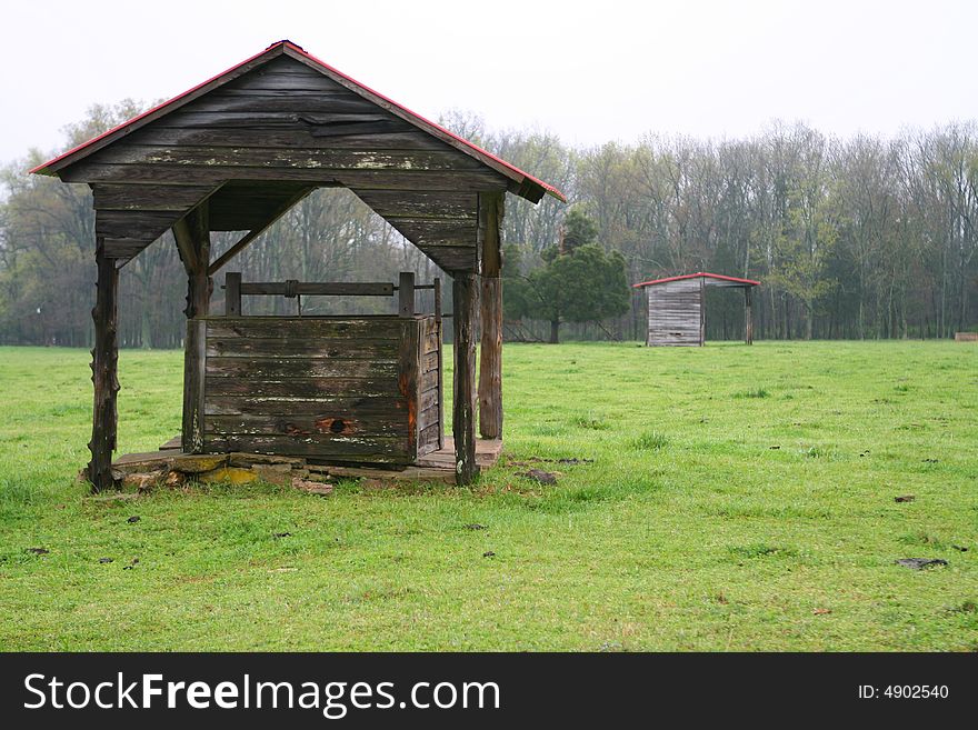 Water well in a meadow set against a dark sky