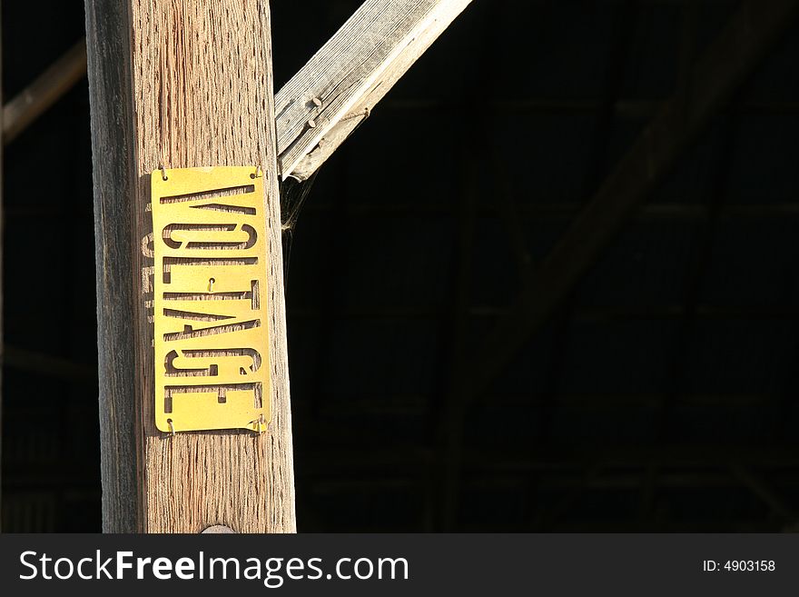 Yellow voltage sign on an old wood post