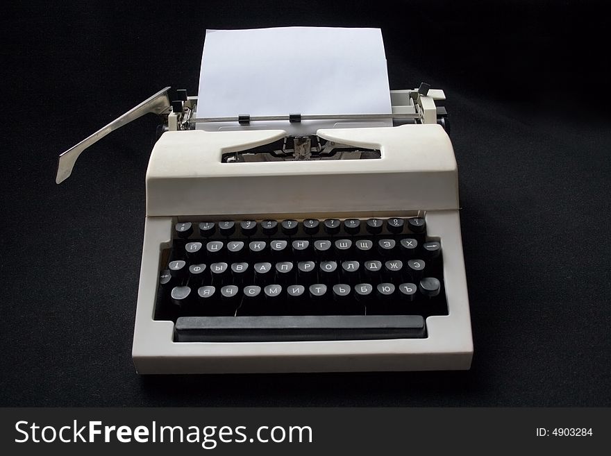 White mechanical typewriter with a paper sheet on a black background. White mechanical typewriter with a paper sheet on a black background