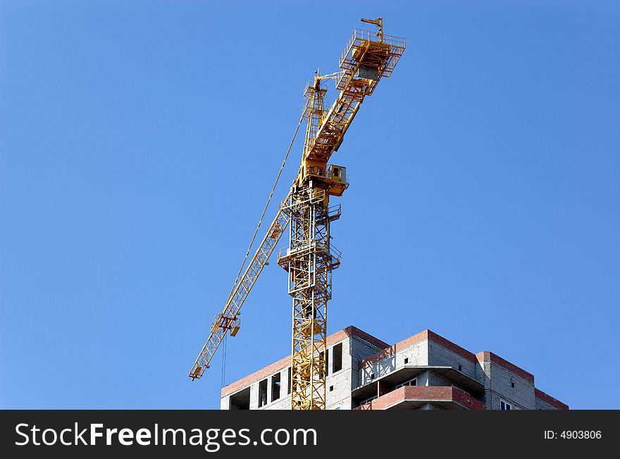 Lifting crane building the house on a blue sky