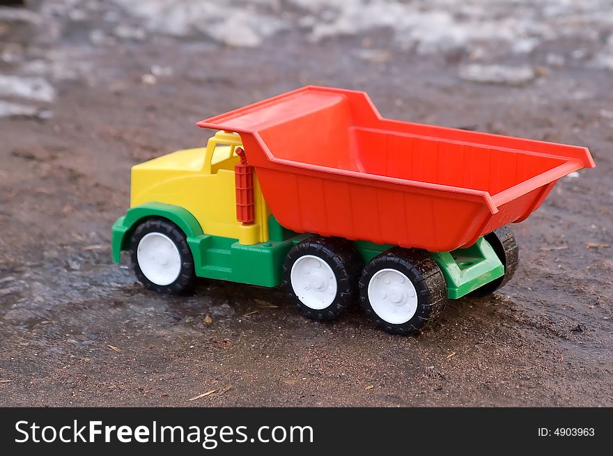 Bright baby toy dump truck in mud