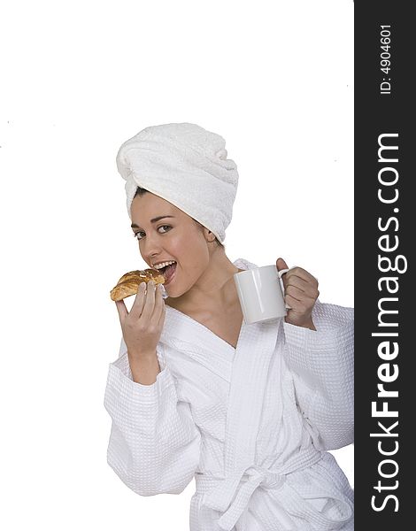 A young woman with bathclothes isolated on white with a cup of milk and a croissant vertical view. A young woman with bathclothes isolated on white with a cup of milk and a croissant vertical view