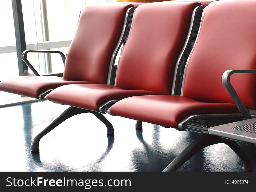 A file of red leather steel chairs in the airport waiting hall. A file of red leather steel chairs in the airport waiting hall.