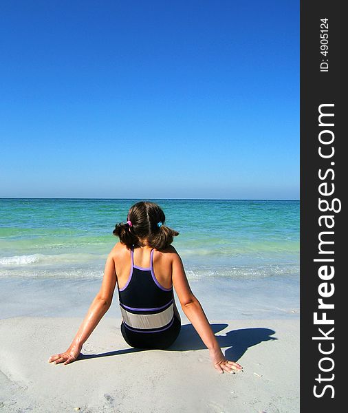 Girl Sitting On The Beach Enjoying The Sun