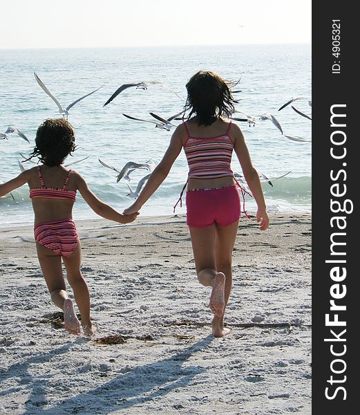 Girls chasing birds on the beach