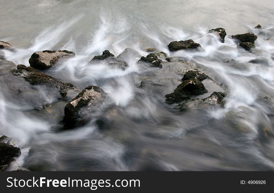 Long exposure shot of the river flowing cross the stones covered with moss. River Kolpa. Dolenjska. Slovenia