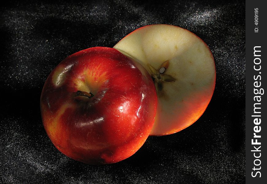 Bright red apple cut hand-and-half on black velvet