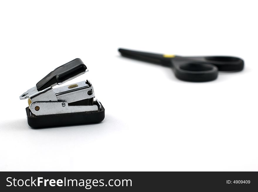 Stapler with safe scissors in the background isolated on white with shallow depth of field