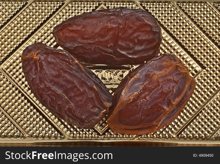 Close-up of three Tunisian dates on golden textured background