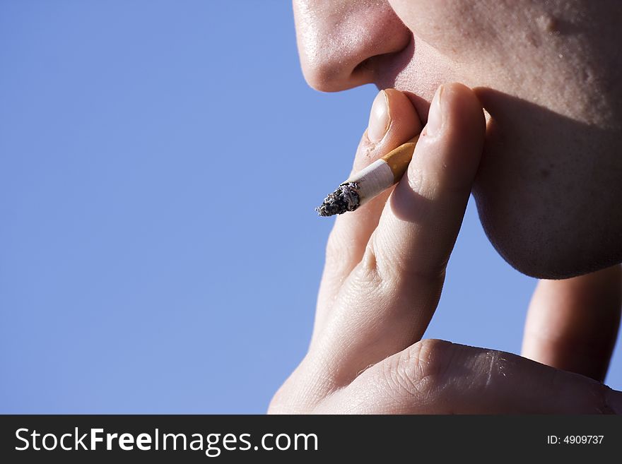 Man smoking cigarette on sky background. Man smoking cigarette on sky background