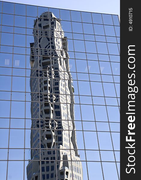 A new construction tower reflected in a blue glass office building. A new construction tower reflected in a blue glass office building