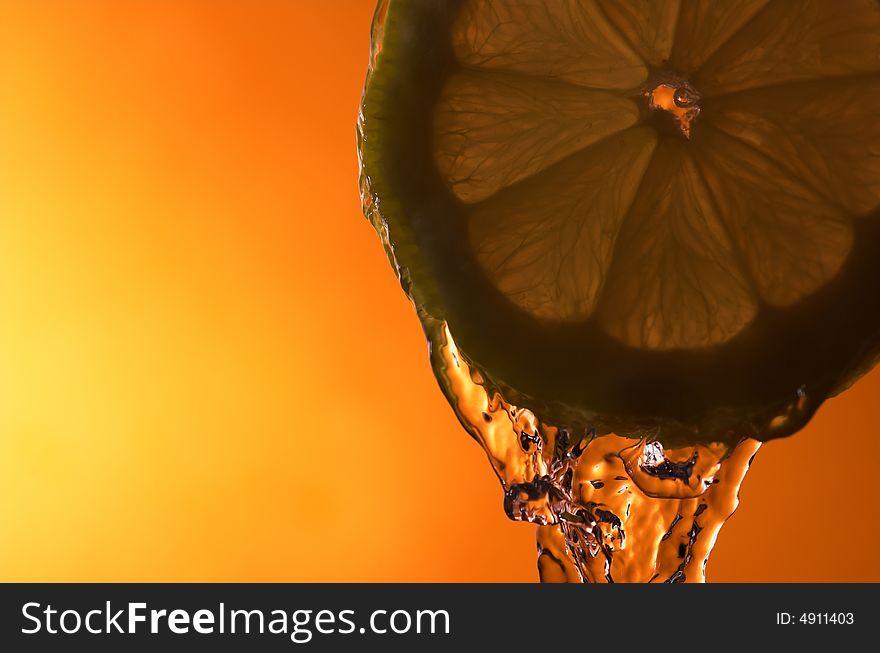 Lemon slice and water over orange background - back lit. Lemon slice and water over orange background - back lit