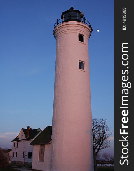 The setting sun cast a warm glow over the historic lighthouse set before a rising moon and clear blue sky.  It has guarded the point where Lake Ontario turns into the St. Lawrence River for over 100 years. The setting sun cast a warm glow over the historic lighthouse set before a rising moon and clear blue sky.  It has guarded the point where Lake Ontario turns into the St. Lawrence River for over 100 years.