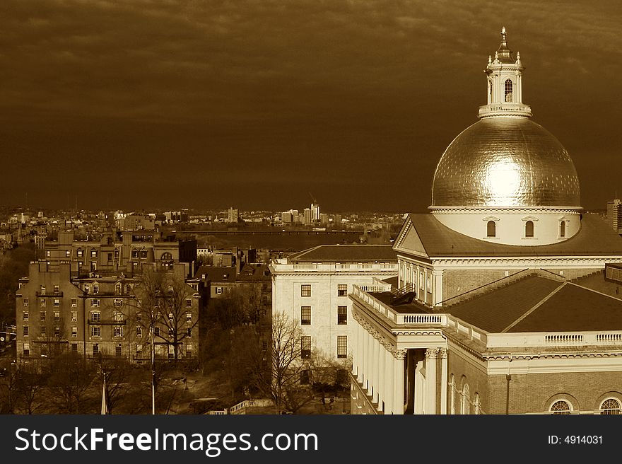 Clouds battel the sunshine as the golden dome of the massachusetts state house glows in this dramatic sepia toned image. Clouds battel the sunshine as the golden dome of the massachusetts state house glows in this dramatic sepia toned image