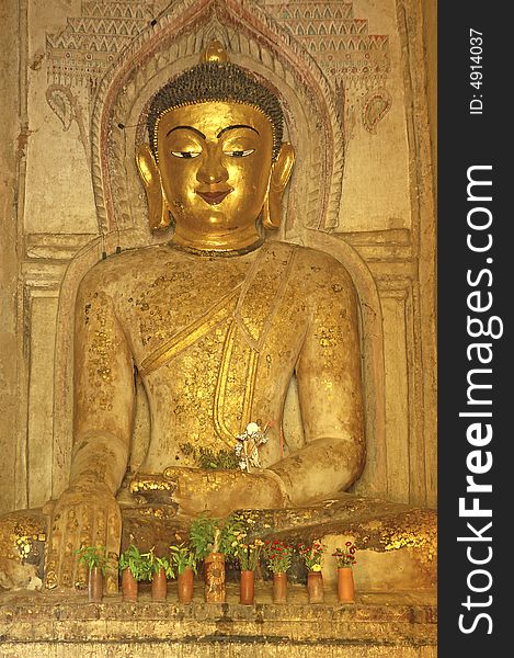 Myanmar, Bagan: Statue in a pagoda representing a seated buddha sculpture in golden color