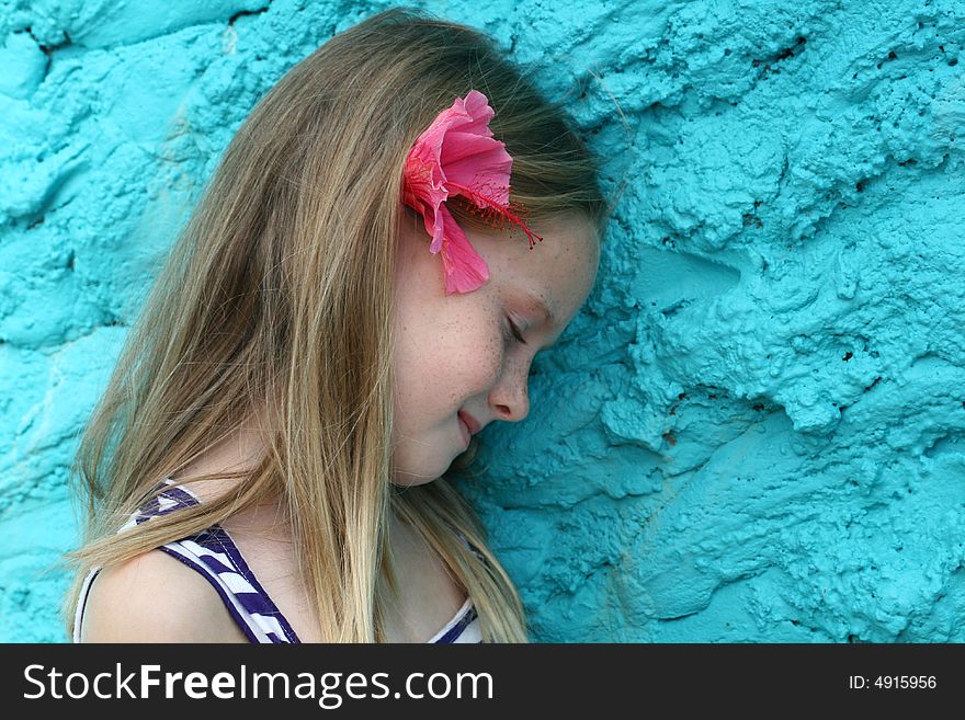 A white caucasian girl child with a pink flower in her hair with her eyes closed taking a rest