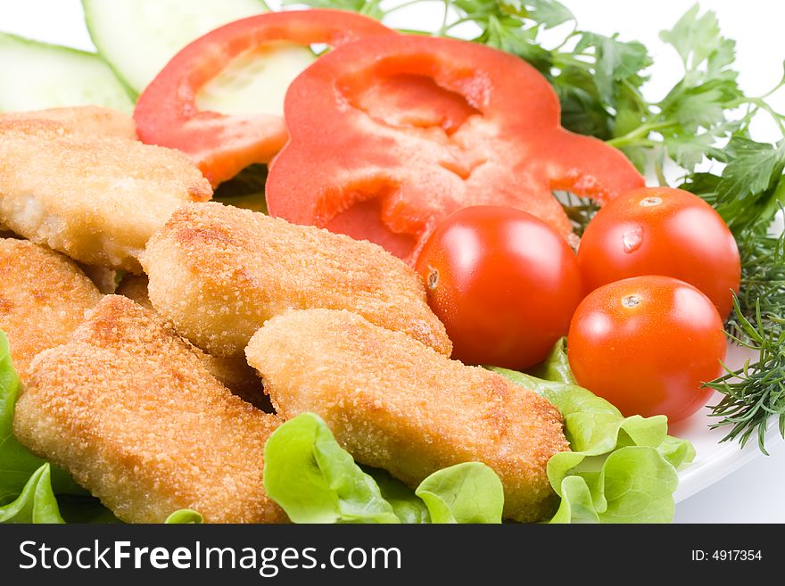 Appetizing fried chicken nuggets with tomatoes, cucumber and pepper on salad leaves. Close-up. Selective focus. Appetizing fried chicken nuggets with tomatoes, cucumber and pepper on salad leaves. Close-up. Selective focus.