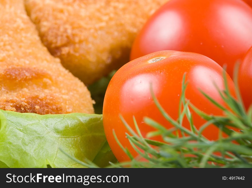 Appetizing fried chicken nuggets  with tomatoes, cucumber and pepper on salad leaves. Close-up. Selective focus. Appetizing fried chicken nuggets  with tomatoes, cucumber and pepper on salad leaves. Close-up. Selective focus.