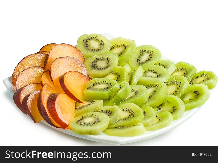 Sliced kiwi and plum on a plate. Isolated on a white background. Clipping path included.