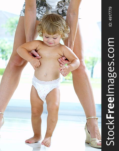 High key portrait of nice baby walking between  mamaâ€™s legs. High key portrait of nice baby walking between  mamaâ€™s legs