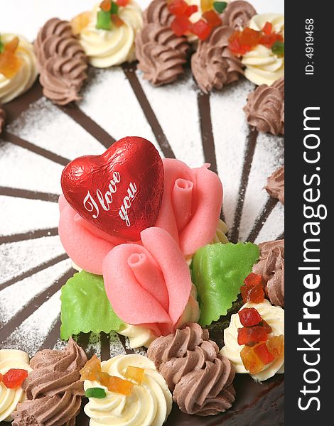 Chocolate cake with pink roses decoration and red heart.