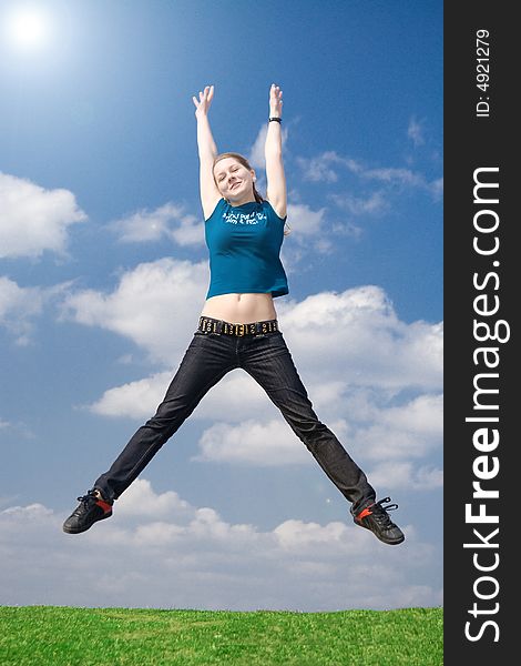 The happy jumping girl on a background of the blue sky