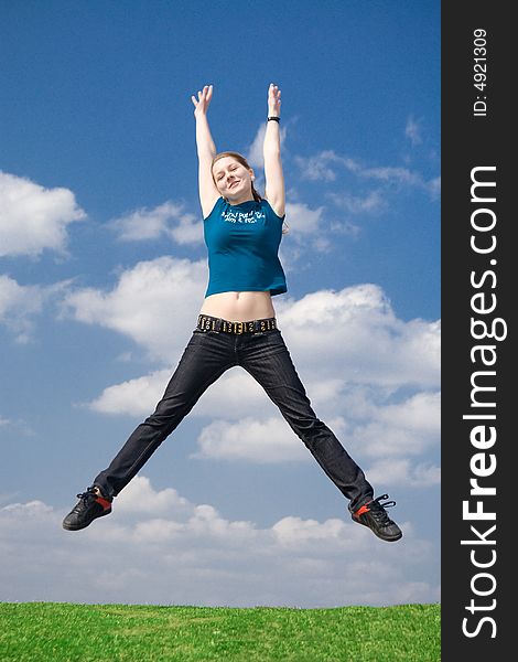 The happy jumping girl on a background of the blue sky