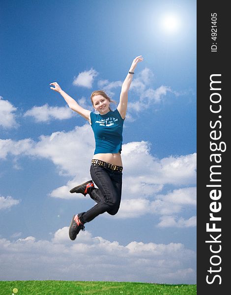 The happy jumping girl on a background of the blue sky