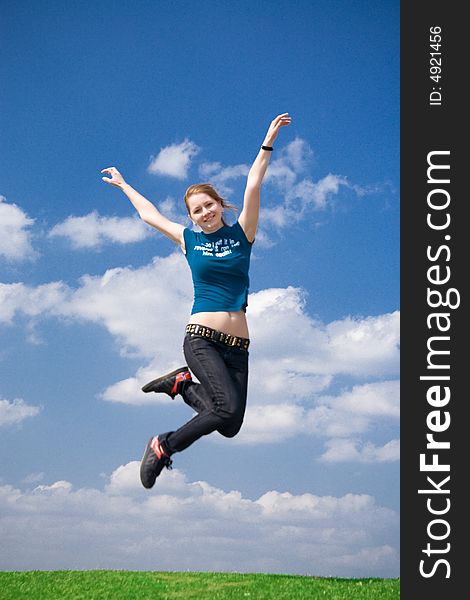 The happy jumping girl on a background of the blue sky