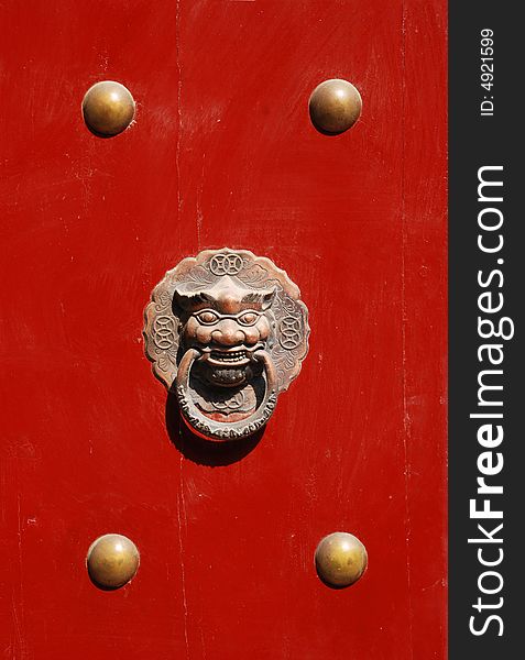 The Chinese red lacquered wood door with bronze lion head and nailheads. The Chinese red lacquered wood door with bronze lion head and nailheads.