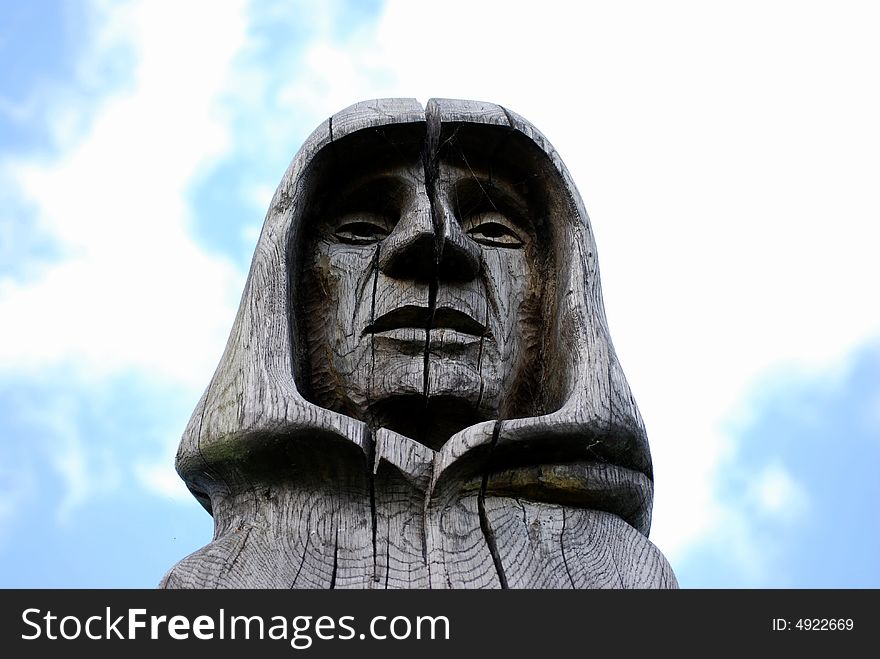 The head of a carved statue of a monk against the blue sky. The head of a carved statue of a monk against the blue sky