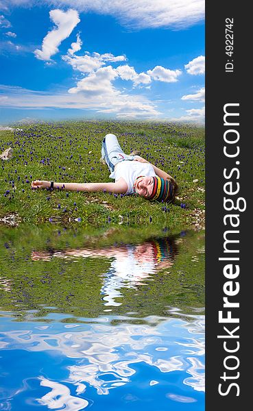 A girl lies on a lawn ashore lake