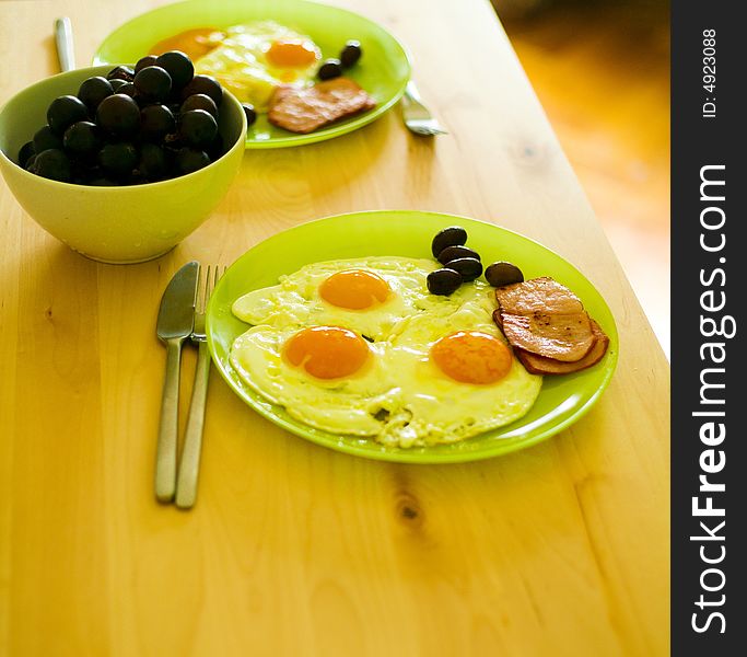 Breakfast food with eggs, bacon, grapes and olives