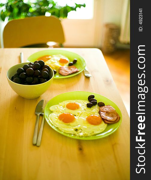 Breakfast food with eggs, bacon, grapes and olives