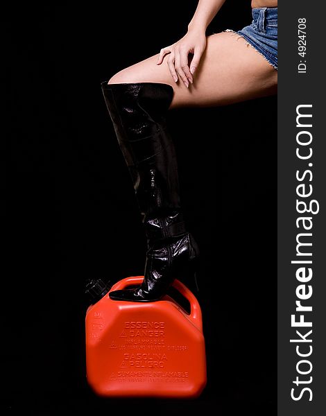 Woman leg wearing long black leather high heel boot one foot on a red gas tank. Woman leg wearing long black leather high heel boot one foot on a red gas tank